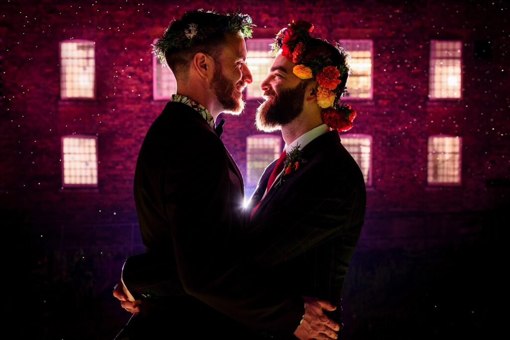 Grooms with flower crowns smiling at each other
